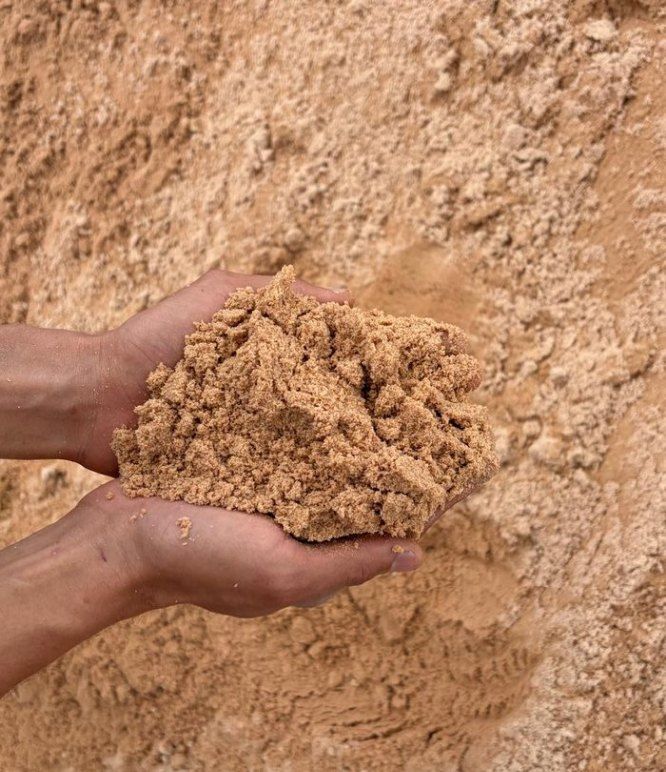 Areia fina nas mãos, sobre pilha de areia