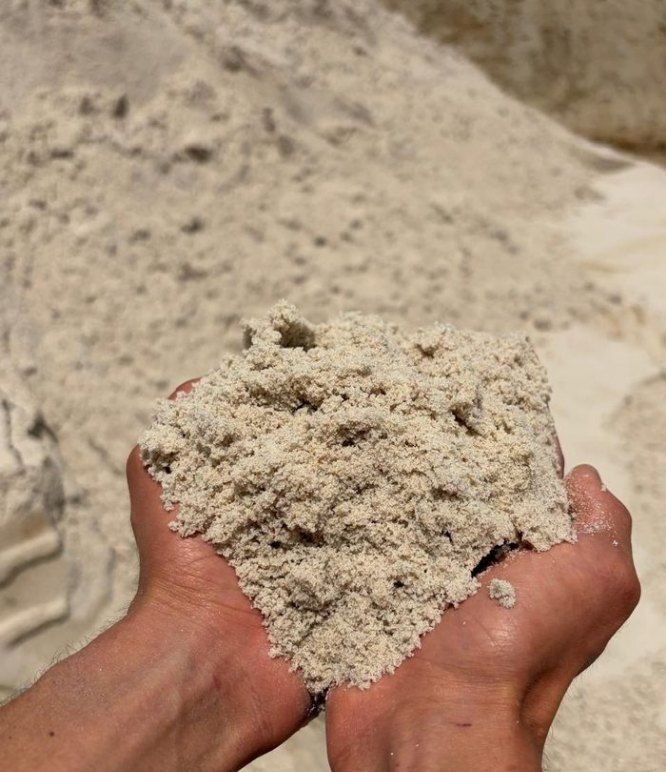 Areia média fina nas mãos, sobre pilha de areia