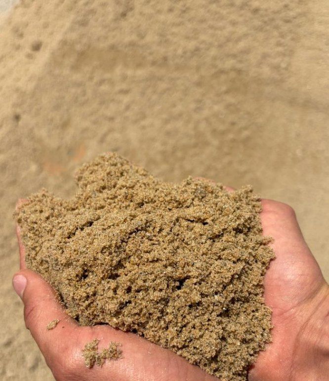 Areia média lavada nas mãos, sobre pilha de areia